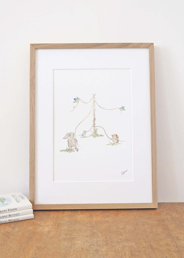Framed nursery print of woodland animals dancing around a maypole, illustrated by Carla Gebhard.